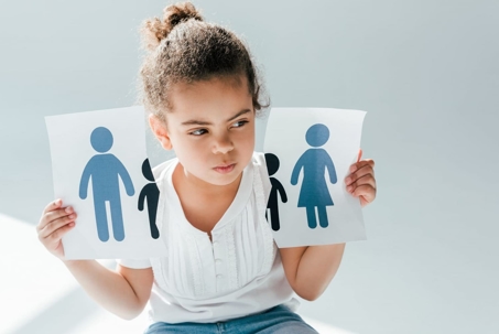 A girl holding a sign with two drawings representing her separated parents